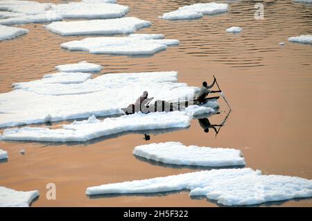 Neu-Delhi, Indien. November 2021. Ein Fischer fährt in einem Boot und versucht, eine dicke Schicht giftigen Schaums zu überqueren, die auf dem Fluss Yamuna in der Nähe von Kalindi Kunj schwimmt. Der weiße Schaum wurde durch kritische hohe Luftverschmutzung und Kontamination aus nahegelegenen Fabriken erzeugt. Am 9. November 2021 in Neu-Delhi, Indien. (Foto: Ravi Batar/ Eyepix Group) Quelle: Eyepix Group/Alamy Live News Stockfoto