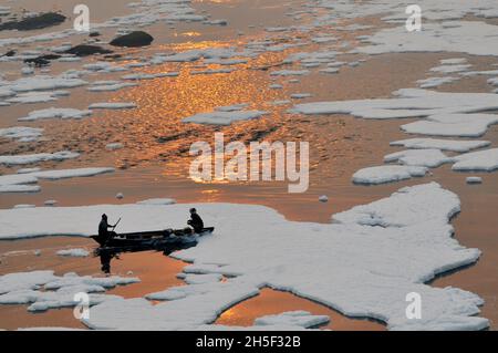 Neu-Delhi, Indien. November 2021. Ein Fischer fährt in einem Boot und versucht, eine dicke Schicht giftigen Schaums zu überqueren, die auf dem Fluss Yamuna in der Nähe von Kalindi Kunj schwimmt. Der weiße Schaum wurde durch kritische hohe Luftverschmutzung und Kontamination aus nahegelegenen Fabriken erzeugt. Am 9. November 2021 in Neu-Delhi, Indien. (Foto: Ravi Batar/ Eyepix Group) Quelle: Eyepix Group/Alamy Live News Stockfoto