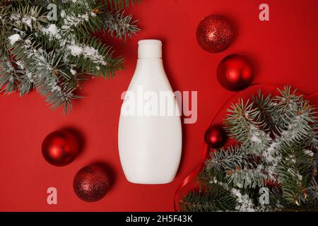 Kosmetik-Produkt Lotion oder Shampoo auf rotem weihnachtshintergrund mit Tannenbaum und Dekorationen, flach legen. Winterpflege Stockfoto