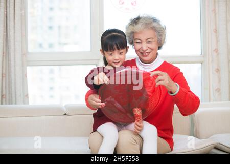 Oma und Enkelin, die gemeinsam Papierschnitte für das neue Jahr anstellen Stockfoto