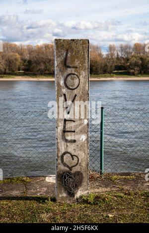 Graffiti (Love) auf einer Steinsäule am Rheinufer im Stadtteil Niehl, Köln, Deutschland. Graffiti auf einer Steinsaeule am Rheinufer Stockfoto