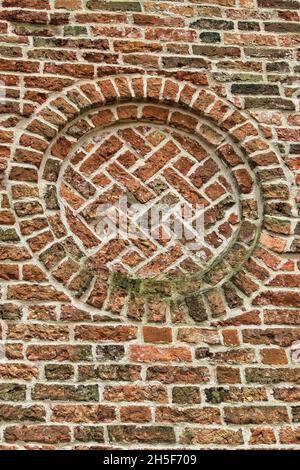 Gemauerte Rosette in einer Mauer aus mittelalterlichem Mauerwerk; römisch-gotische Kirche aus dem 12. Jahrhundert in Tinallinge, Provinz Groningen, Niederlande Stockfoto