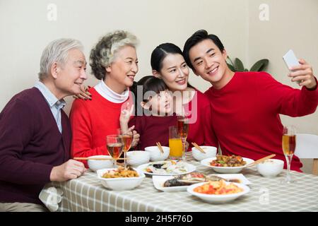 Fröhliche Familie, die beim Neujahrsessen zusammen Fotos macht Stockfoto