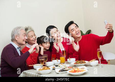 Fröhliche Familie, die beim Neujahrsessen zusammen Fotos macht Stockfoto