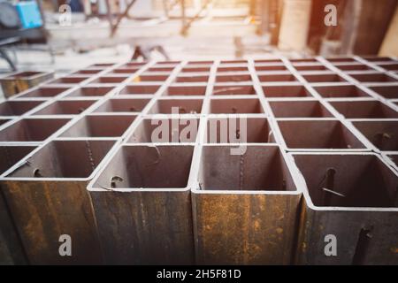 Eine Reihe von quadratischen Metallrohlingen. Lager Metallwalzen. Stockfoto