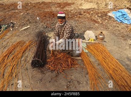 Srinagar, Jammu Und Kaschmir, Indien. November 2021. Am Stadtrand von Srinagar schälen Dorfbewohner aus Kaschmir die Haut von Korbstäben. Wicker wird für die Herstellung von traditionellen Feuerstellen namens kangri in kaschmir verwendet. Kashmiris verwenden diese traditionellen Feuerköpfe, um sich in den schweren Wintermonaten, wenn die Temperatur auf minus 20 abgeht, warm zu halten. Kangri besteht aus Ton und Zweigen, in denen heiße Kohle gehalten wird. (Bild: © Sajad HameedZUMA Press Wire) Stockfoto