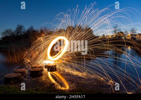 Leichte Malerei mit Stahlwolle; pyrotechnische Darstellung bei Nacht mit Spiegelung im Wasser. Stockfoto