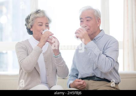 Glückliches altes Paar, das Milch trinkt Stockfoto