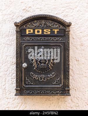 Alte Vintage-Briefkasten an der Wand mit modernem Schloss in Schwarz und Gold Stockfoto