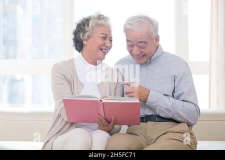 Glückliches altes Paar, das zusammen das Fotoalbum anschaut Stockfoto
