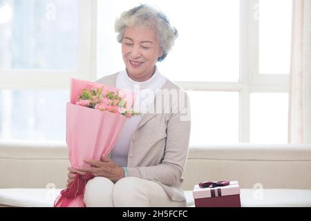 Alte Frau, die Blumen in der Hand hält Stockfoto