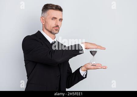 Foto von serious handsome reifen ceo Manager gekleidet hält Arme Sanduhr isoliert grauen Hintergrund Stockfoto