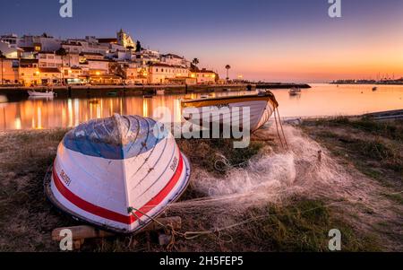 Ferragudo ist ein kleines Fischerdorf an der Küste der portugiesischen Algarve. Hier sehen wir das Dorf am frühen Abend. Stockfoto