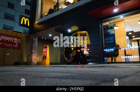 Busan, Südkorea - 19. März 2018: Nachtstraße mit, Lieferroller steht am Eingang zum McDonalds Fast-Food-Restaurant Stockfoto
