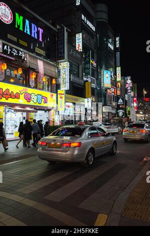 Busan, Südkorea - 23. März 2018: Vertikaler Straßenblick bei Nacht mit farbenfroher Werbebeleuchtung stehen Menschen und Autos auf der Straße in der Innenstadt Stockfoto