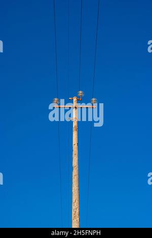 Strom in der Vergangenheit. Sehr alter Mast mit Drähten und Kabeln gegen blauen Himmel Stockfoto