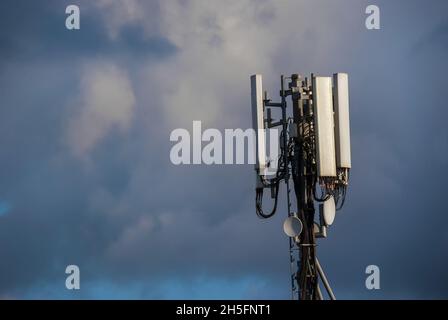 Elektromagnetische Strahlung. Telekommunikationsturm mit 5G- und 4G-Antennen zwischen den Wolken (mit Kopierplatz) Stockfoto