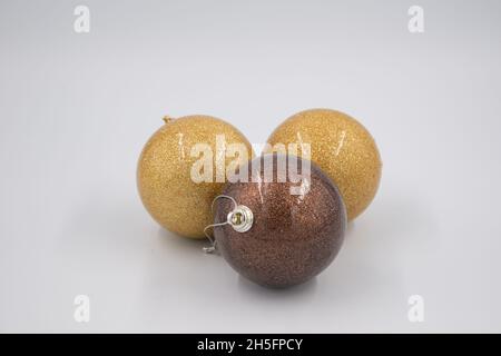 Drei Weihnachtskugeln, golden und braun isoliert auf weißem Hintergrund. Stockfoto
