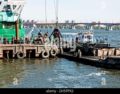 Reinigung der neu entstandenen Insel von Industrieabfällen am Dnjepr River durch einen Bagger. Umweltprobleme moderner Flüsse. Ökologisches Konzept. Stockfoto