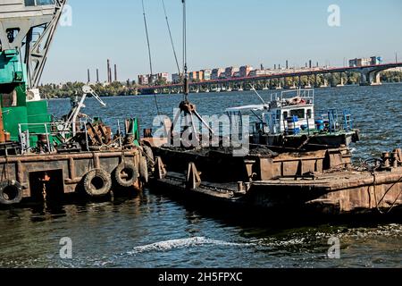 Reinigung der neu entstandenen Insel von Industrieabfällen am Dnjepr River durch einen Bagger. Umweltprobleme moderner Flüsse. Ökologisches Konzept. Stockfoto