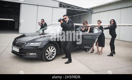 Professionelle bewaffnete Team von weiblichen und männlichen Bodyguards schützen Prominenten Person in der Auto-Limousine. Sicherheitsschutz für Bodyguard und VIP-Personen. Bekennen Stockfoto