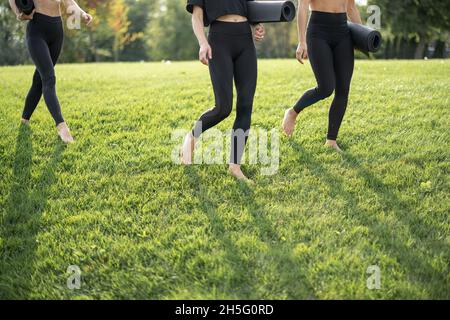 Mädchen mit Fitnessmatten in Sportbekleidung auf Gras Stockfoto