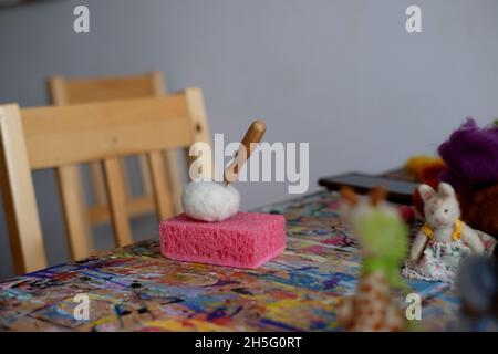 Nadel in einem gefilzten Würfel auf einem rosa Schwamm. Zubehör für Nadelfilz, Weben von Wolle handgefertigte Handwerk von Schafhaar. . Hochwertige Fotos Stockfoto