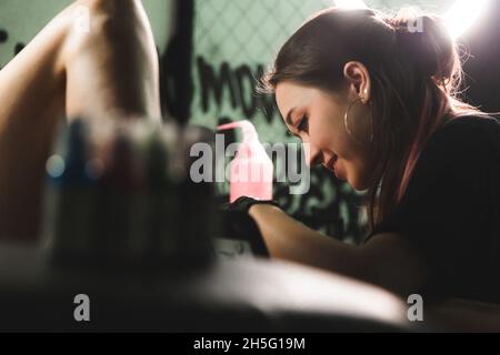 Frau Tattoo Künstler tun Tattoo im Studio, Tätowierung am Körper. Nahaufnahme Stockfoto