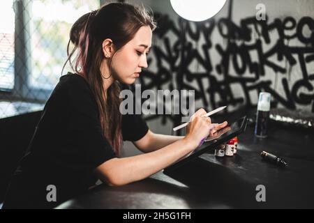 Portrait einer professionellen Tätowiererin in einem Tattoo-Studio zeichnet eine Skizze auf ein Tablet Stockfoto