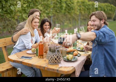 Mann, der auf dem Smartphone Fotos von Freunden beim Picknick gemacht hat Stockfoto