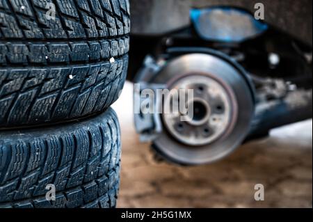 Winterreifen neben dem Auto, saisonales Reifenwechselkonzept, selektiver Fokus, Fokus auf Reifen, Nahaufnahme Stockfoto