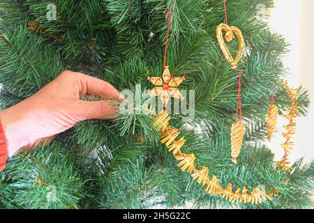 Dekorieren Weihnachtsbaum auf hellem Hintergrund. Hand hält eine weihnachtsbaumdekoration. Konzept für Weihnachten und Neujahr. Stockfoto