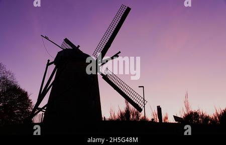 Silhouette einer alten Windmühle, die in früheren Jahrhunderten zur Herstellung von Mehl in der Dämmerung verwendet wurde. Es wurde vor Jahrhunderten von einem niederländischen Baumeister hergestellt Stockfoto