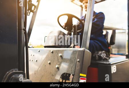 Ein Mann auf einem Gabelstapler arbeitet in einem großen Lager, lädt Säcke von Rohstoffen Stockfoto