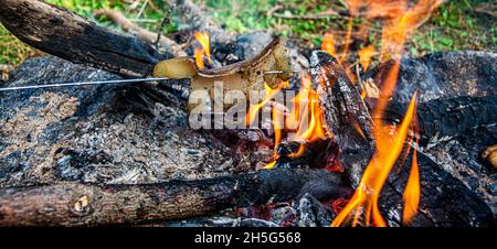 Gebratener Speck auf Lagerfeuer Flamme im Garten. Stockfoto