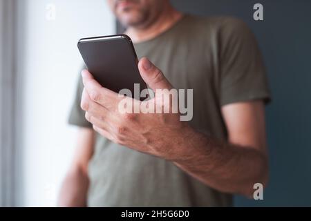 Mann, der SMS auf dem Handy liest, selektiver Fokus auf Hand und Gerät Stockfoto