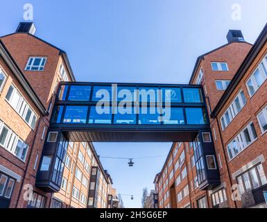 Stockholm, Schweden - 15. April 2021: Hohe Brücke aus Metall und Glas über der Straße zwischen zwei Gebäuden Stockfoto