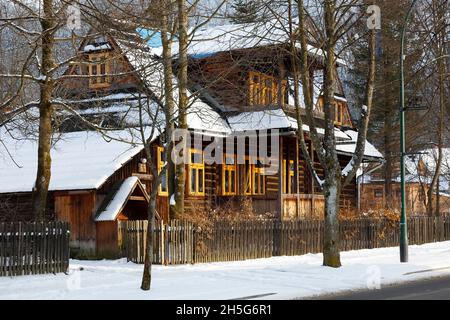 Zakopane, Polen - 21. März 2018: Hinter den Bäumen und dem Holzzaun befindet sich eine Holzvilla, die lokal Koszysta genannt wird. Dieses historische Gebäude stammt aus der Zeit Stockfoto