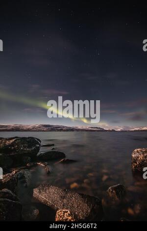 Borealis aurora fegt bei einer wolkenlosen Nacht über einen großen See in Kilpisjarvi, Lappland, Finnland. aurora polaris tanzt in Grün über den Himmel. Scandin Stockfoto