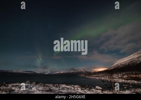 Borealis aurora fegt bei einer wolkenlosen Nacht über einen großen See in Kilpisjarvi, Lappland, Finnland. aurora polaris tanzt in Grün über den Himmel. Scandin Stockfoto