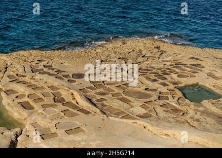 Xwejni Salzpfannen und Xlendi Klippen auf der Insel Gozo, Malta.erstaunliche natürliche Kreationen stammen aus Kalkstein.traditionelle Meersalzproduktion. Stockfoto