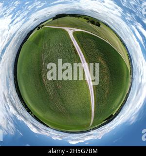 Sphärische abstrakte Panorama-Luftaufnahme in einem Feld mit fantastischen schönen Wolken und einer Rundumbildung des Raums wie ein kleiner Planet Stockfoto