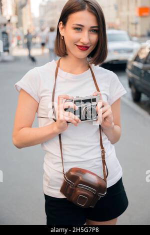 Zwei junge attraktive Mädchen ruhen sich in der Stadt aus, reisen in die Stadt, besichtigen, navigieren durch die Karte, fotografieren mit der Kamera, glücklich Stockfoto