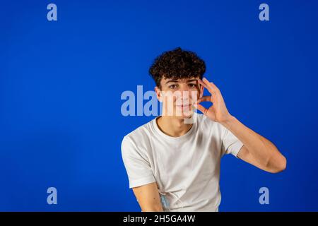 Lustiger charismatischer Vollmann in weißem T-Shirt mit lockigem Haar auf blauem Hintergrund mit nachdenklichem Gesicht. Isoliert Stockfoto