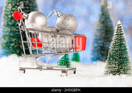 Kauf von Weihnachtsbaumschmuck. Kleine silberne Weihnachtskugeln in einem Supermarktkorb Stockfoto