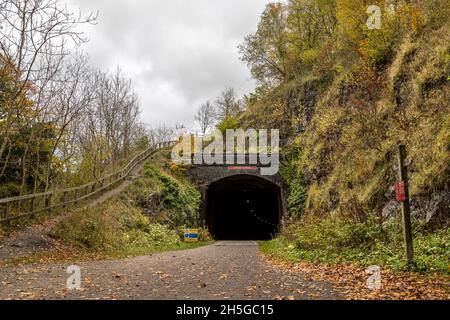 Im November 2021 steigt der Fußweg am Eingang des Litton Tunnels an, während sich orange und braune Blätter auf dem Monsal Trail sammeln. Stockfoto