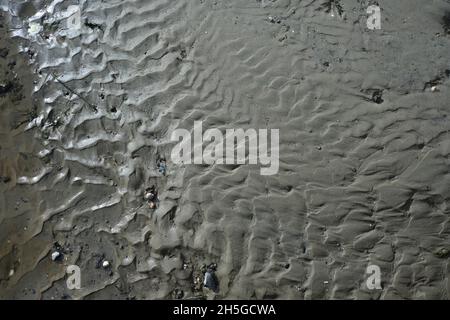 Natürliche strukturierte Oberfläche aus nassem Sand und kleinen Steinen an einem Strand in den niederlanden Stockfoto