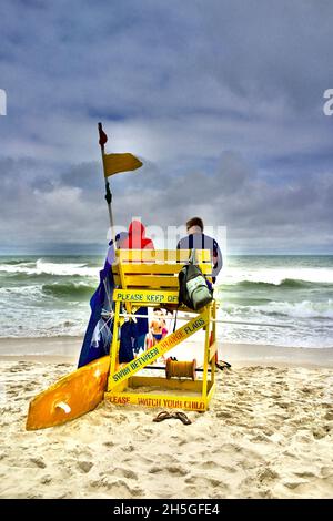 Zwei Rettungsschwimmer sitzen in einem hohen hölzernen Strandstuhl und beobachten Schwimmer am Strand von Long Beach Island, NJ, USA Stockfoto