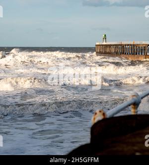 Weißes Wasser, Wellen und Brandung Rollen in der Küstenstadt Whitby, North Yorkshire, hinein und stoßen gegen die Hafenmauer Stockfoto