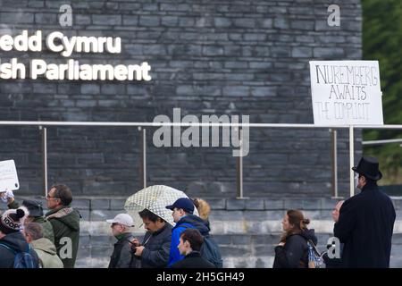 CARDIFF, WALES - 09 2021. NOVEMBER: Ein Protestler mit einem Transparent mit der Aufschrift „Nürnberg erwartet den Mittäter“ auf den Stufen des walisischen Parlaments Stockfoto